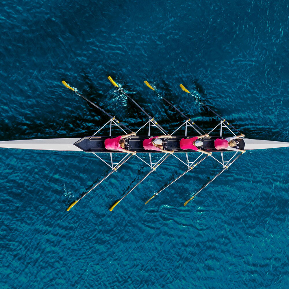 Ruderteam im Gleichklang, Symbol für Teamarbeit, Zusammenarbeit und erfolgreiche Unternehmensentwicklung.