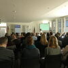 Vortragssituation mit Referentin und Präsentation auf Leinwand während einer Fachveranstaltung.