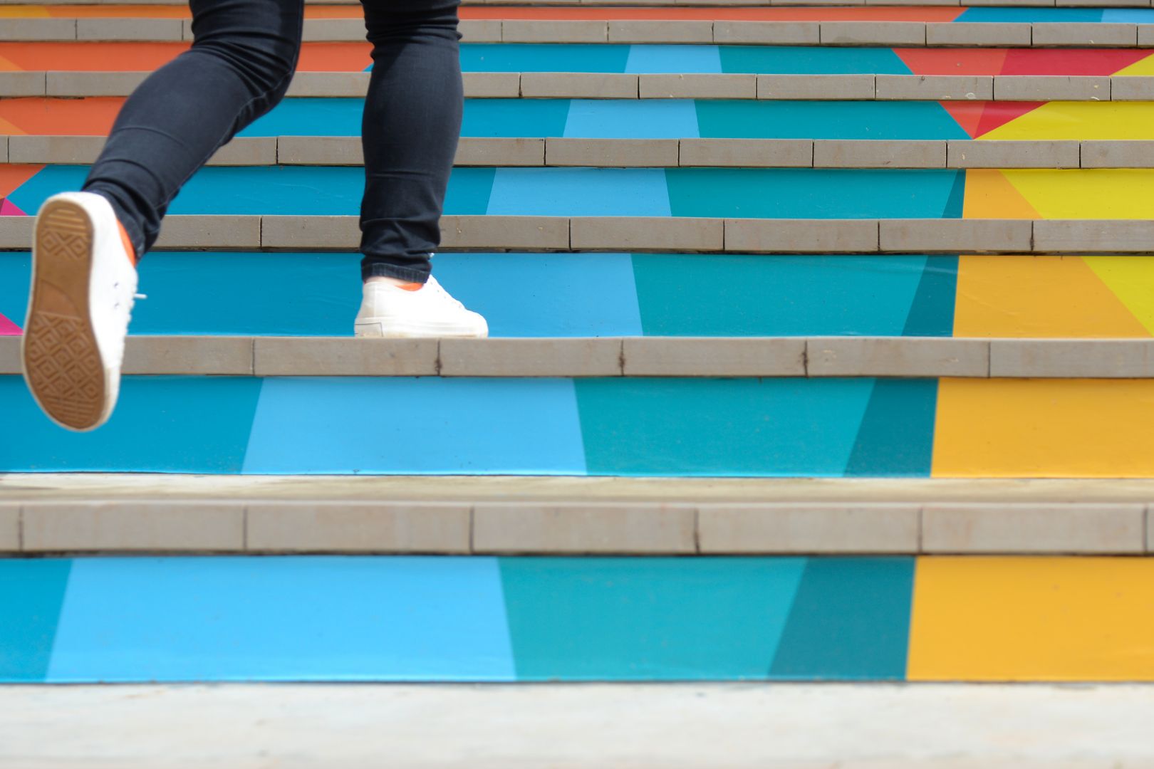 Füße einer Person die eine bunte Treppe hinaufgeht